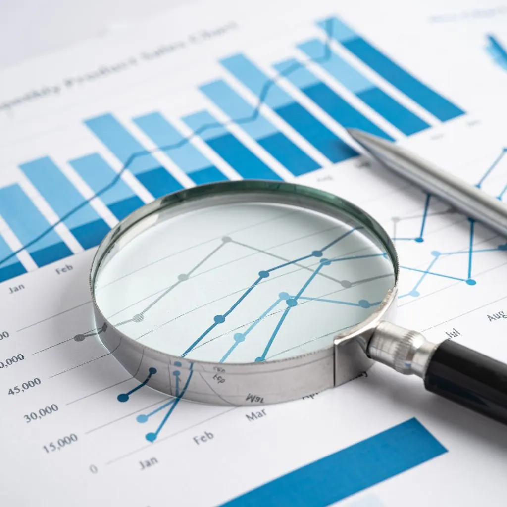 Magnifying glass and a pen on printed line and bar charts